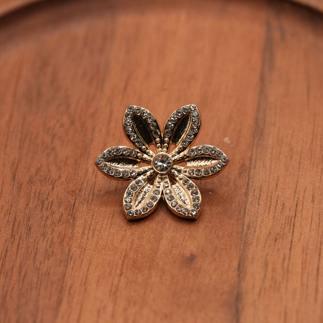 Gold-tone six-petal flower button with reflective border details