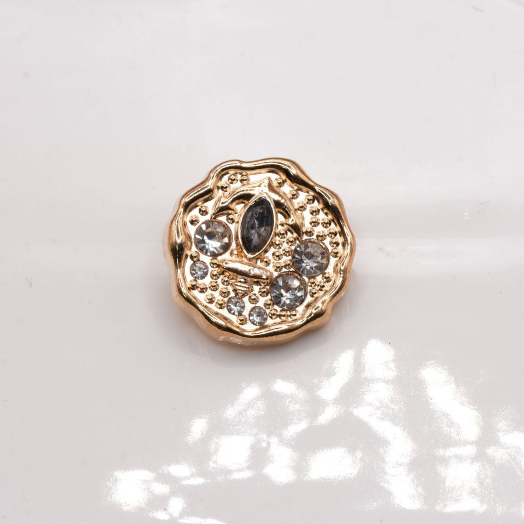 Rose-gold-tone scalloped button face with a raised anchor and round accents.
