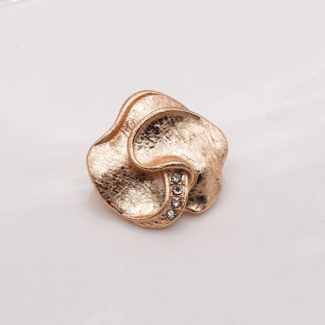 Gold tone lobed button with textured surfaces and a curved ridge