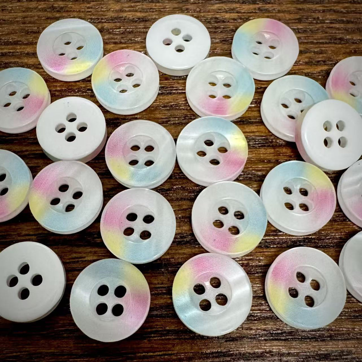 Pastel rainbow four-hole buttons arranged on a neutral surface