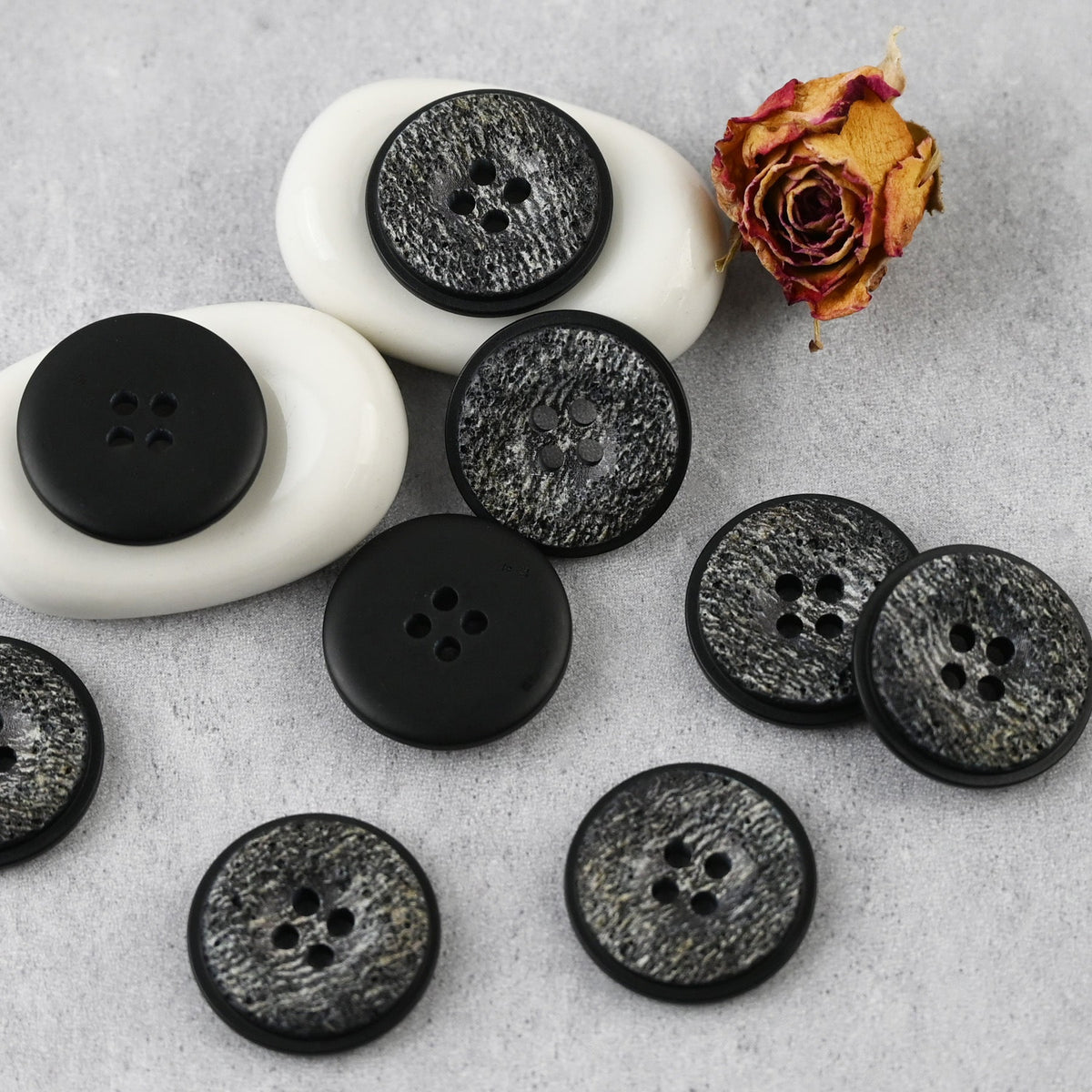 Black-gray pitted four-hole buttons with raised rims