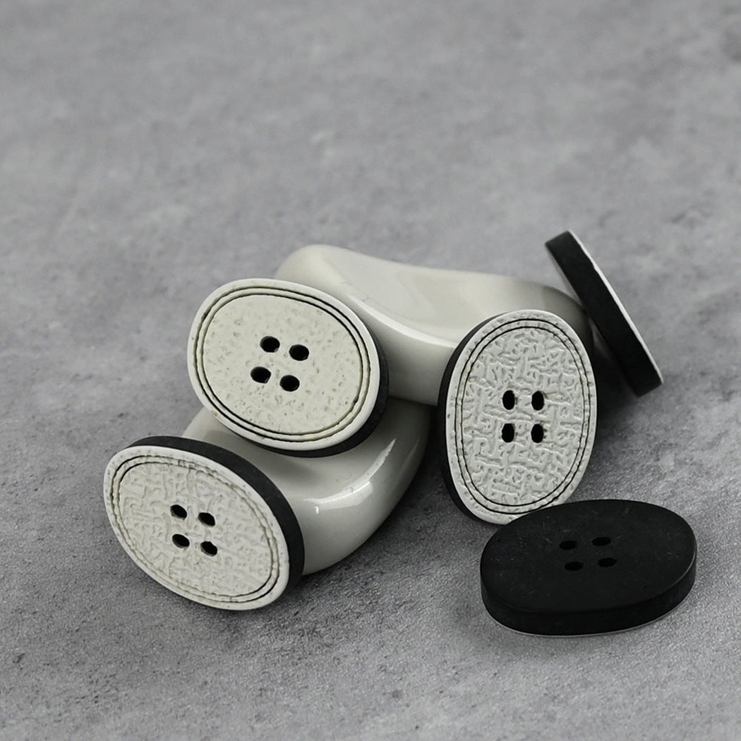Black oval four-hole buttons with textured off-white center panels