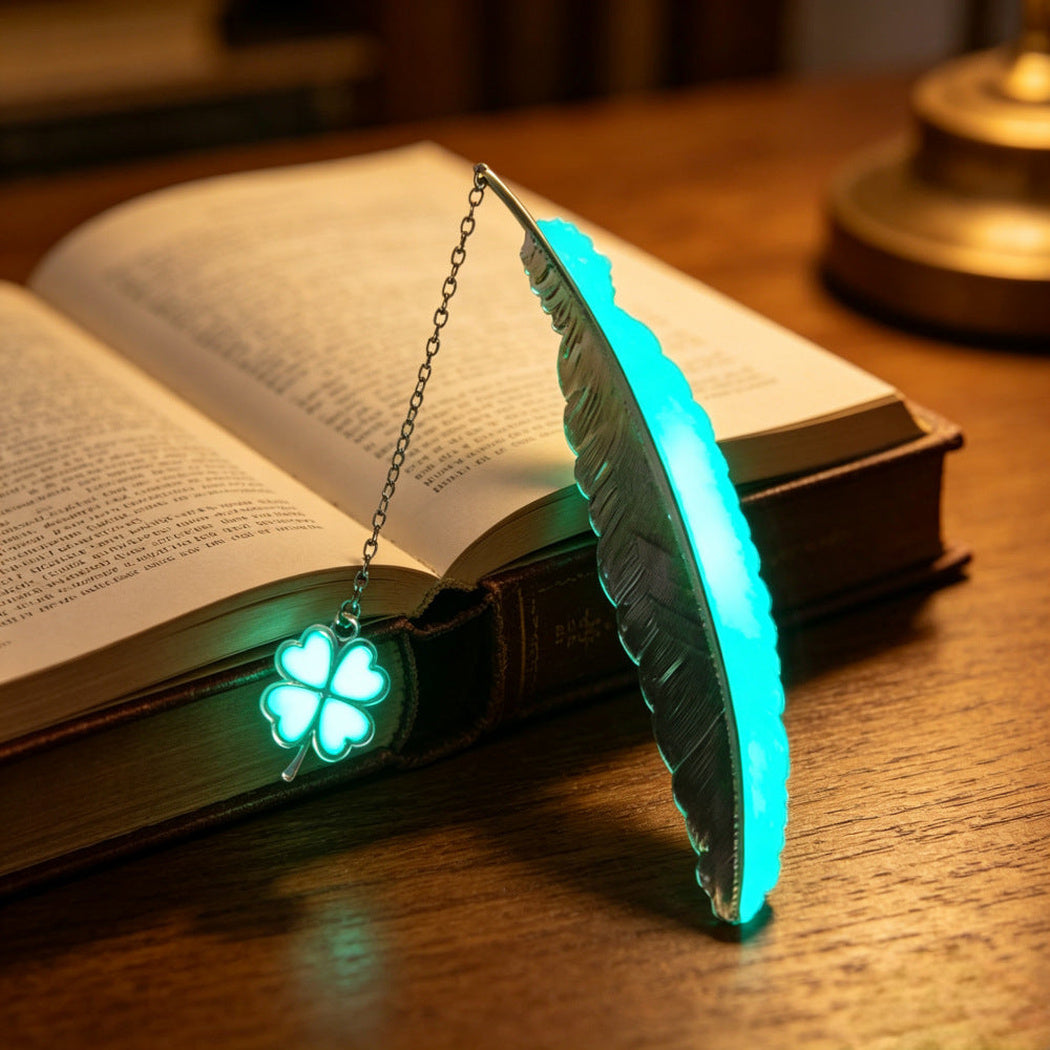 Glowing cyan feather bookmark with four-leaf clover charm on an open book