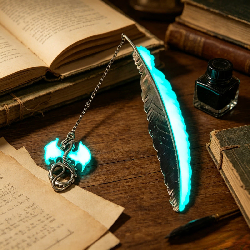 Glowing cyan feather bookmark with dragon charm beside books and ink