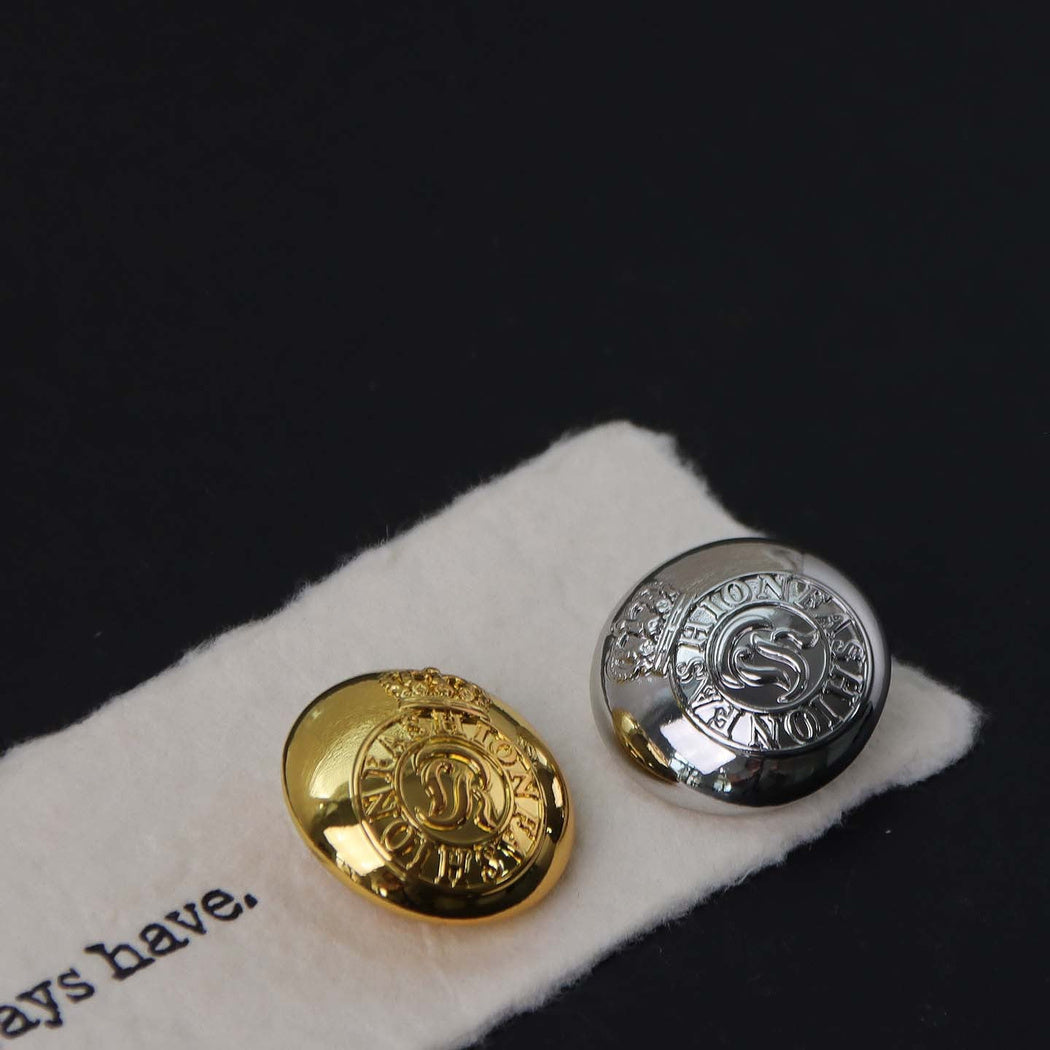 Gold-tone and silver-tone round buttons with raised crowns and circular lettering