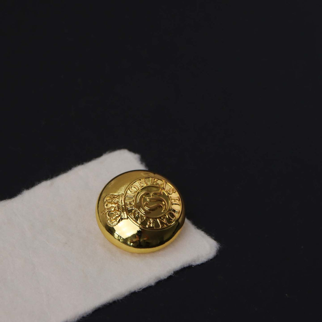 Gold-tone round button with raised crown and circular lettering