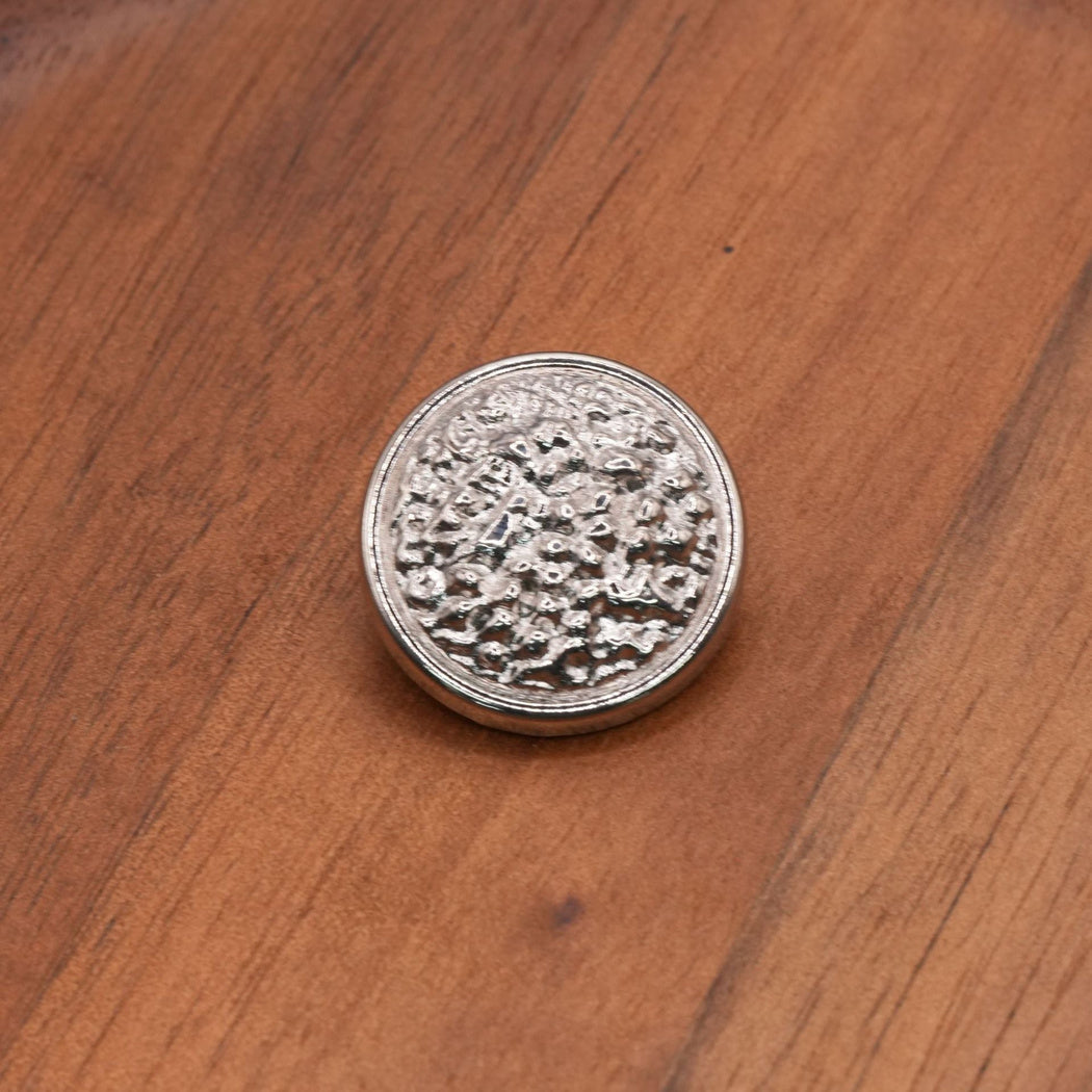 Silver finish round button with an irregular textured face