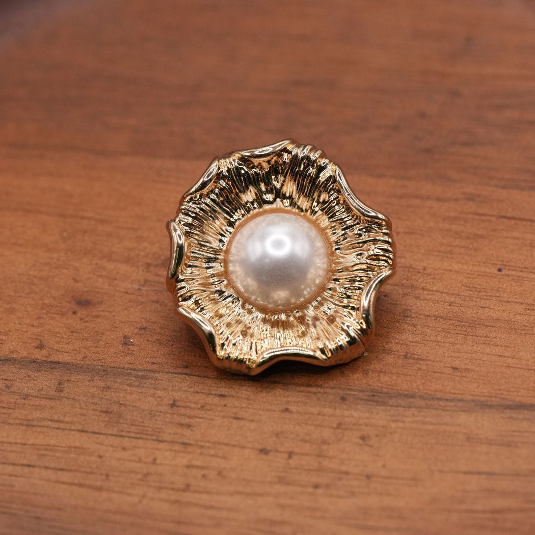 Gold-tone fluted flower button with a white domed center, single front view