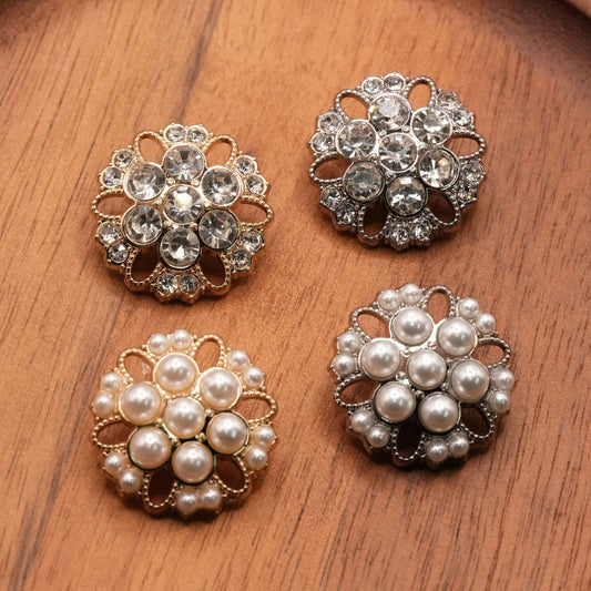 Four open-petal flower buttons with gold-tone and silver-tone frames and clear or white round insets