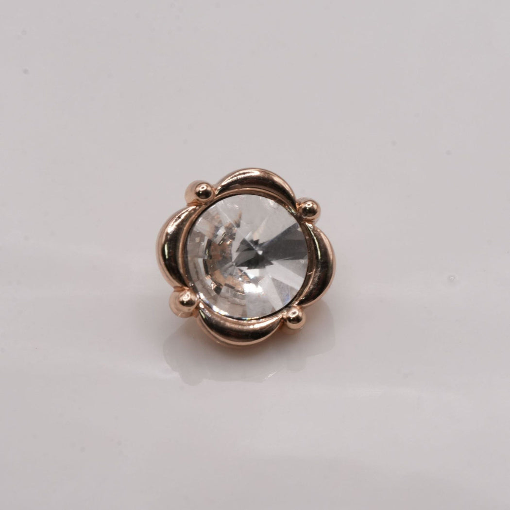 Warm-tone four-lobed button with round accents and clear faceted center