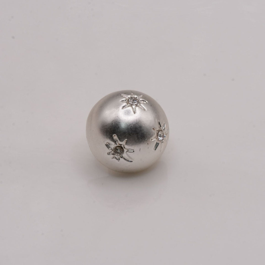 Silver-tone domed button with three starburst decorations and clear centers