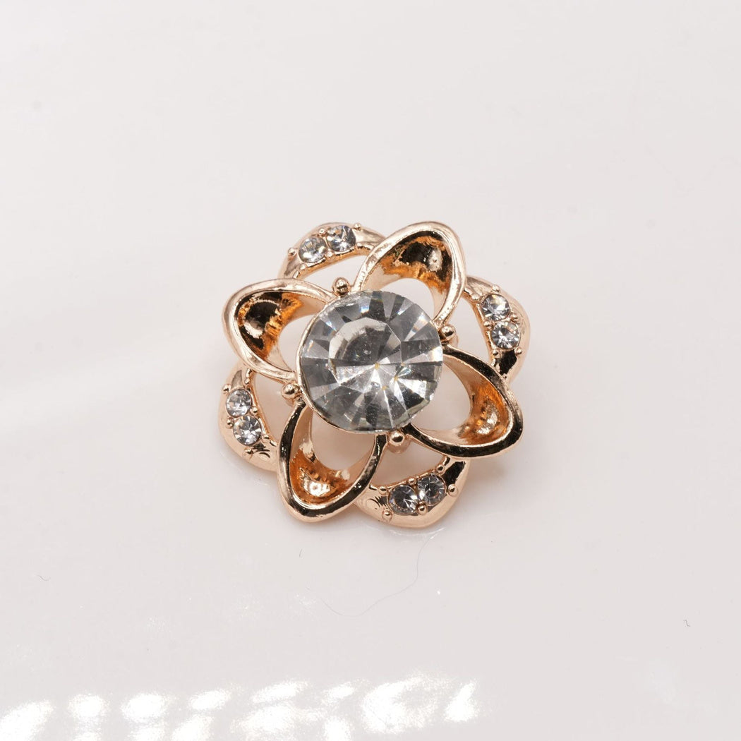 Gold-tone decorative button with open teardrop lobes and clear faceted center
