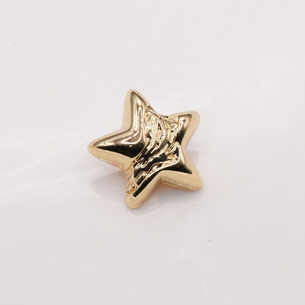 Pale gold tone star button with flowing raised center detail