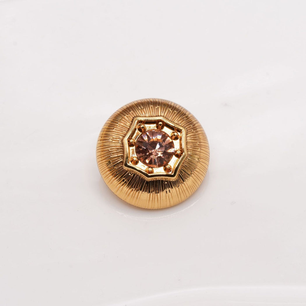 Warm gold-tone round button with radial grooves and a rose-brown faceted center
