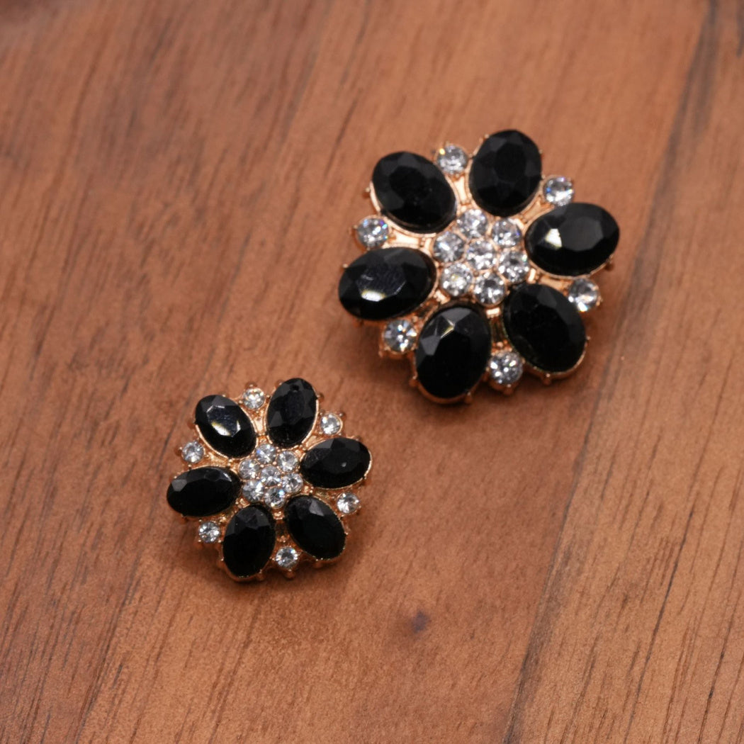Black faceted flower button pair with gold-tone edges and clear center accents