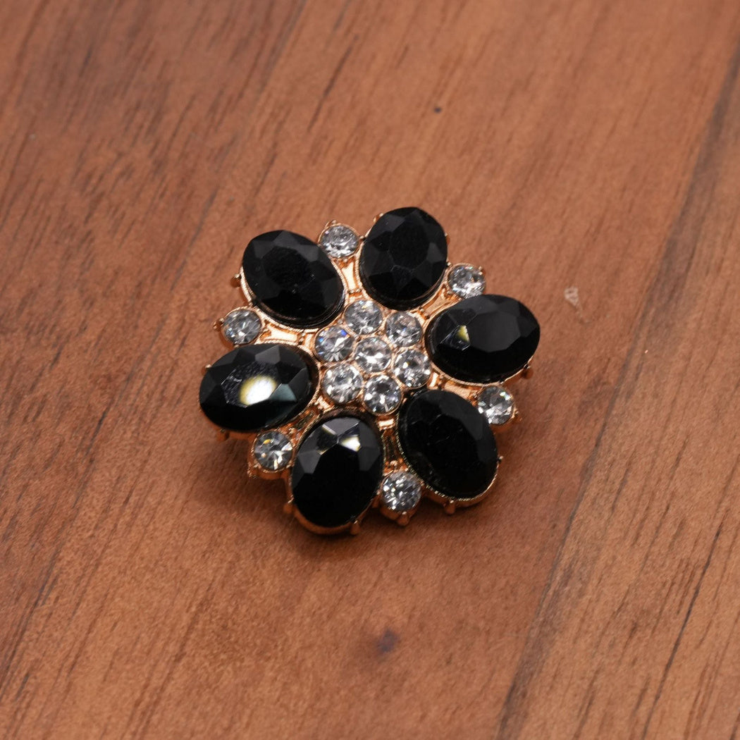 Black faceted flower button with gold-tone settings and a clustered clear center