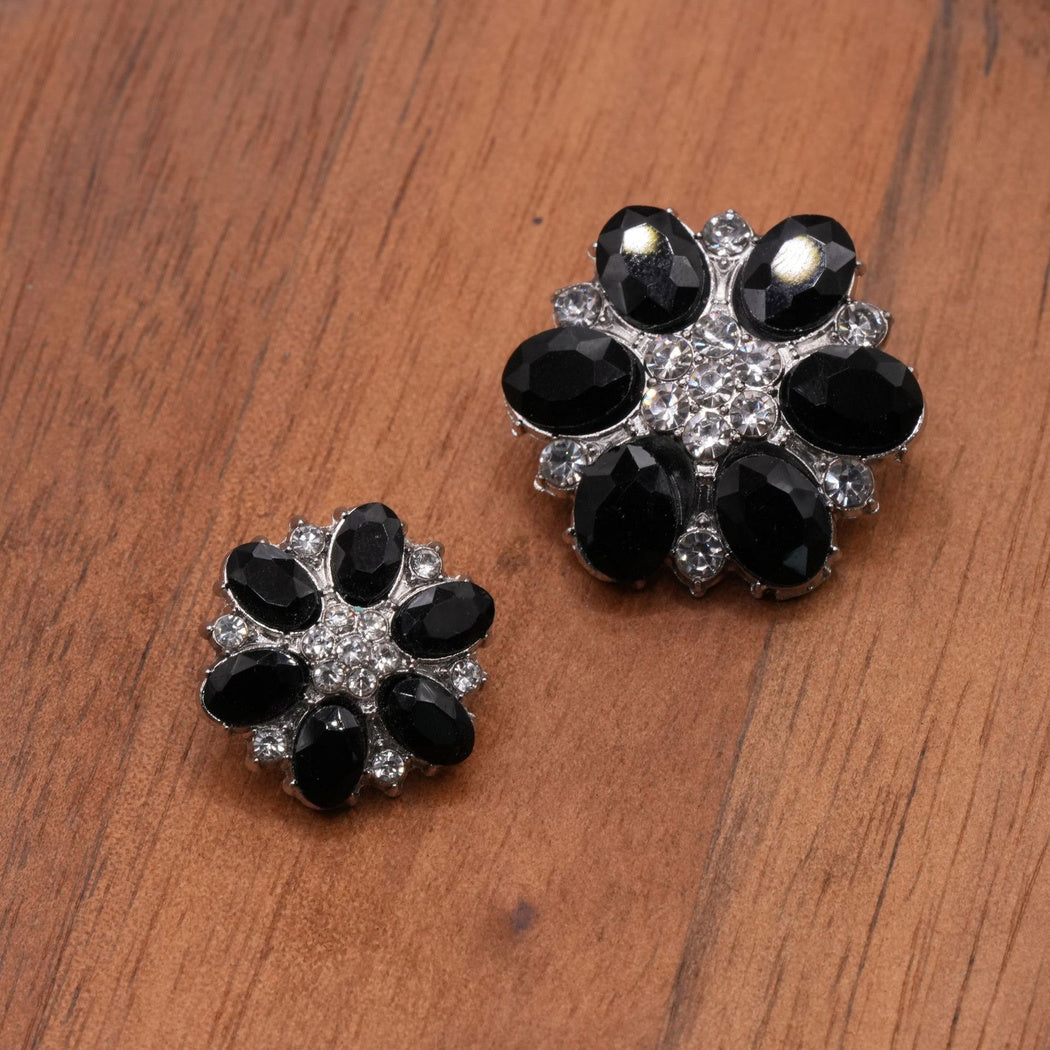 Black faceted flower button pair with silver-tone settings and clear accent clusters