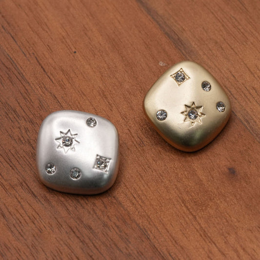 Silver-tone and gold-tone rounded-square buttons with starburst and faceted accents, front overview