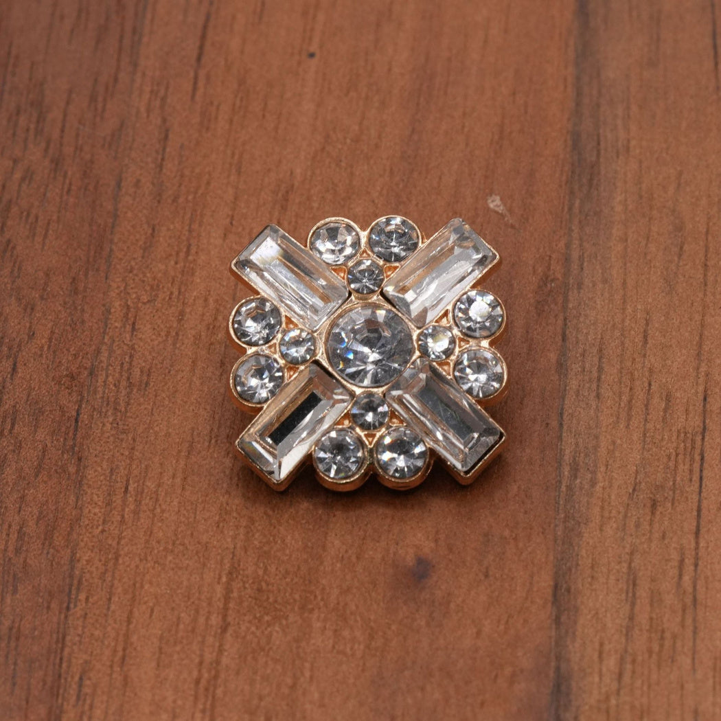 Gold-tone button with a round center and four diagonal faceted inserts, front view