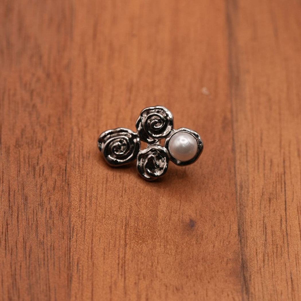 Single silver-colored four-lobed button with spiral details and a pale round dome