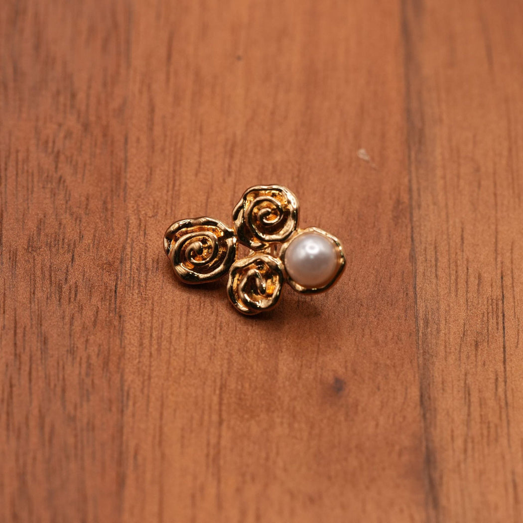 Single gold-colored four-lobed button with curled reliefs and a pale round dome