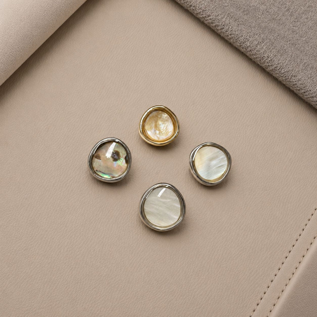 Four irregular rounded buttons with gold-tone and silver-tone rims and varied light and dark centers