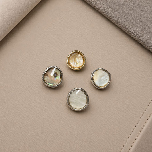 Four irregular rounded buttons with gold-tone and silver-tone rims and varied light and dark centers