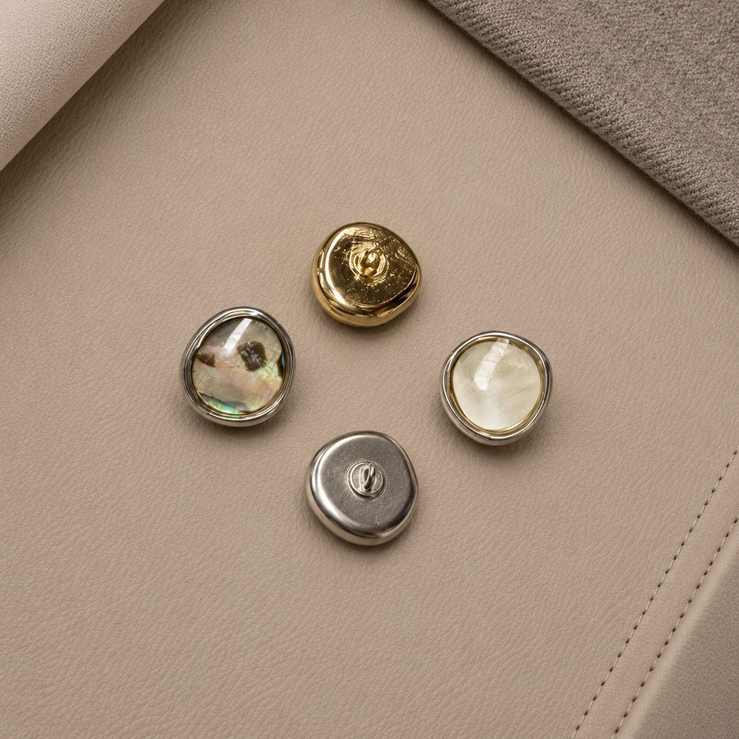 Four rounded buttons showing two fronts and gold-tone and silver-tone backs with sewing loops
