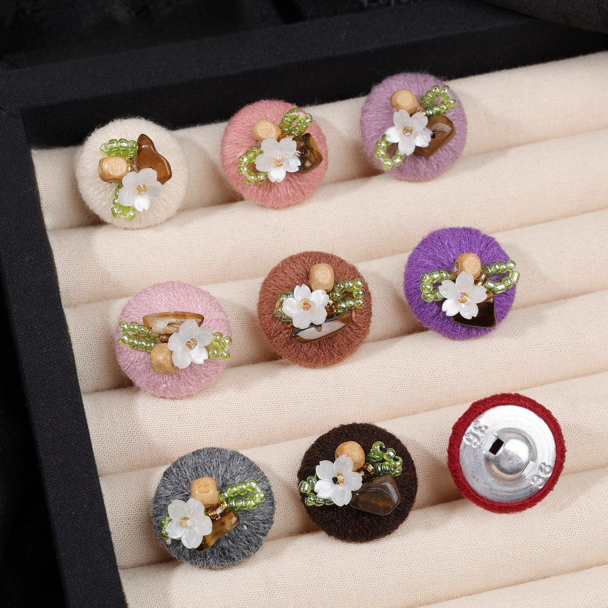 Assorted beaded floral round buttons displayed in a tray