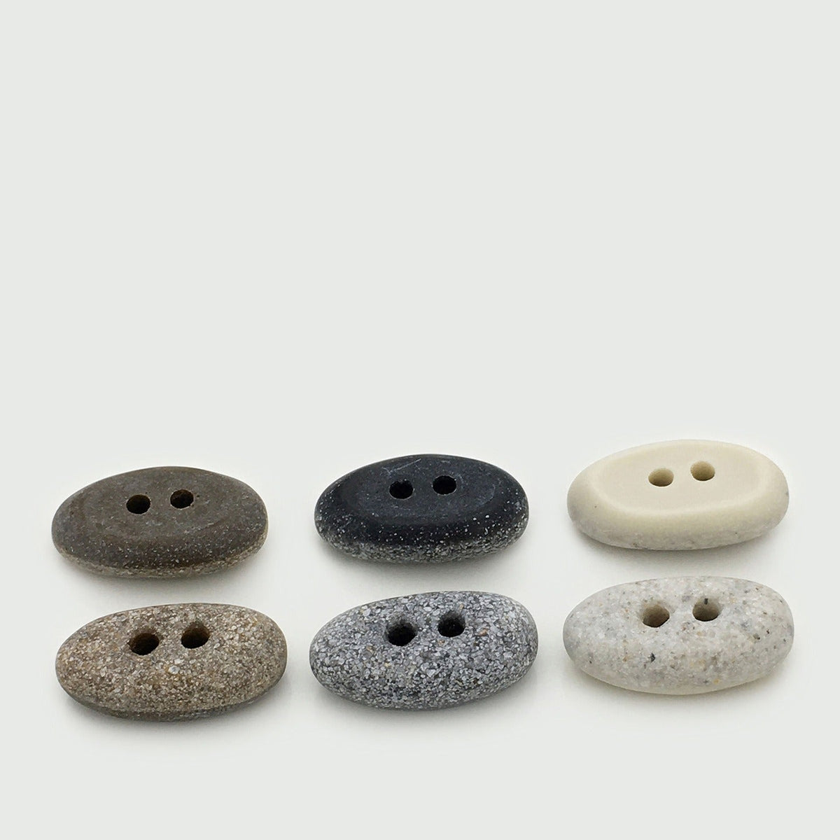 Six oval two-hole buttons in white, brown, gray, and black finishes