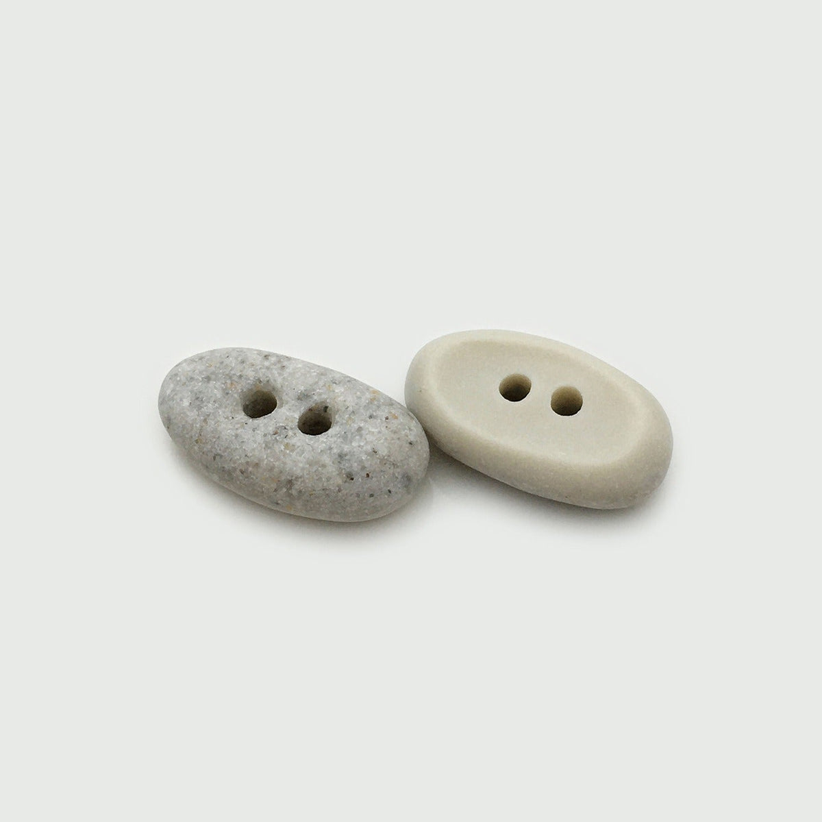 Two white oval two-hole buttons shown at matching angled views