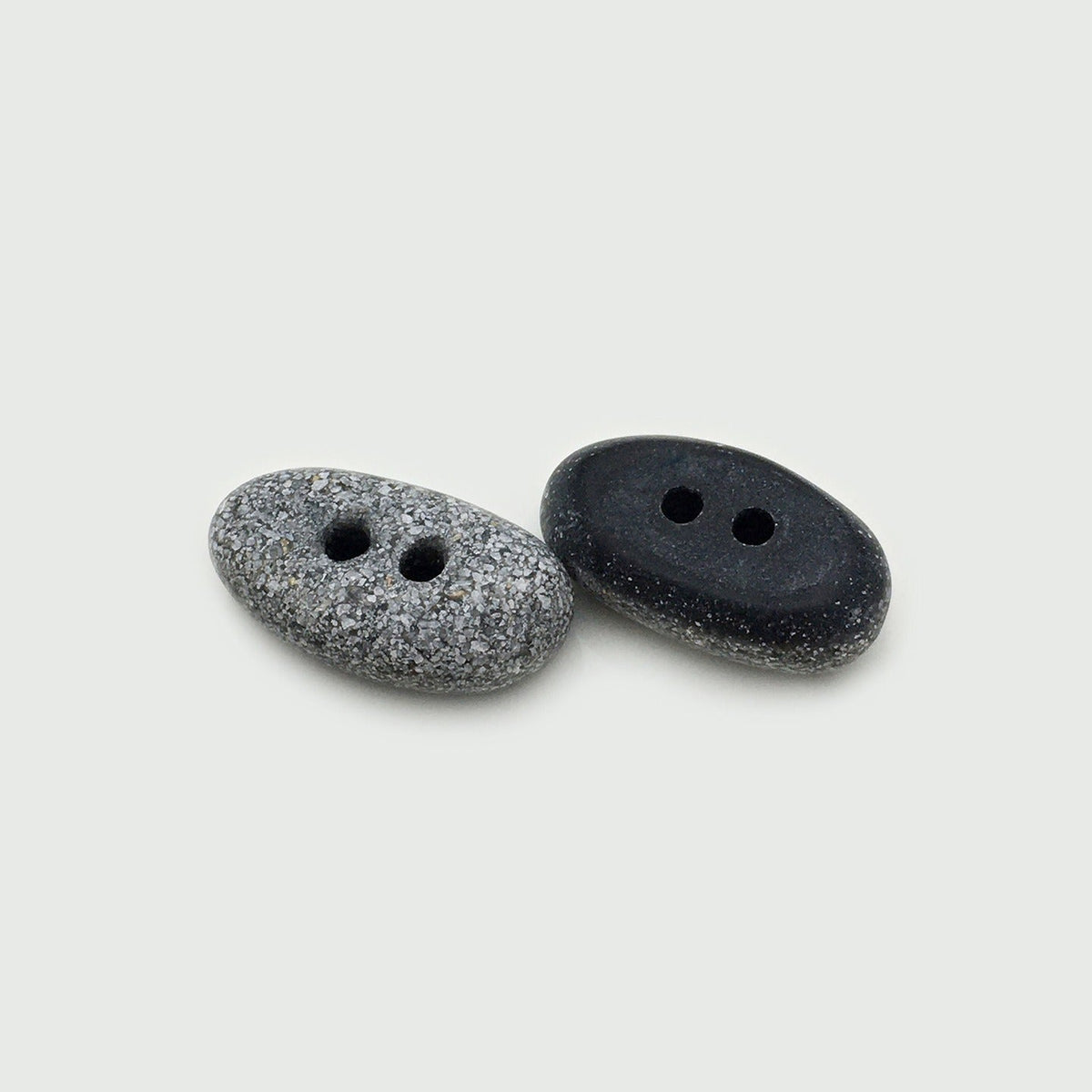 Two black oval two-hole buttons in speckled and solid styles