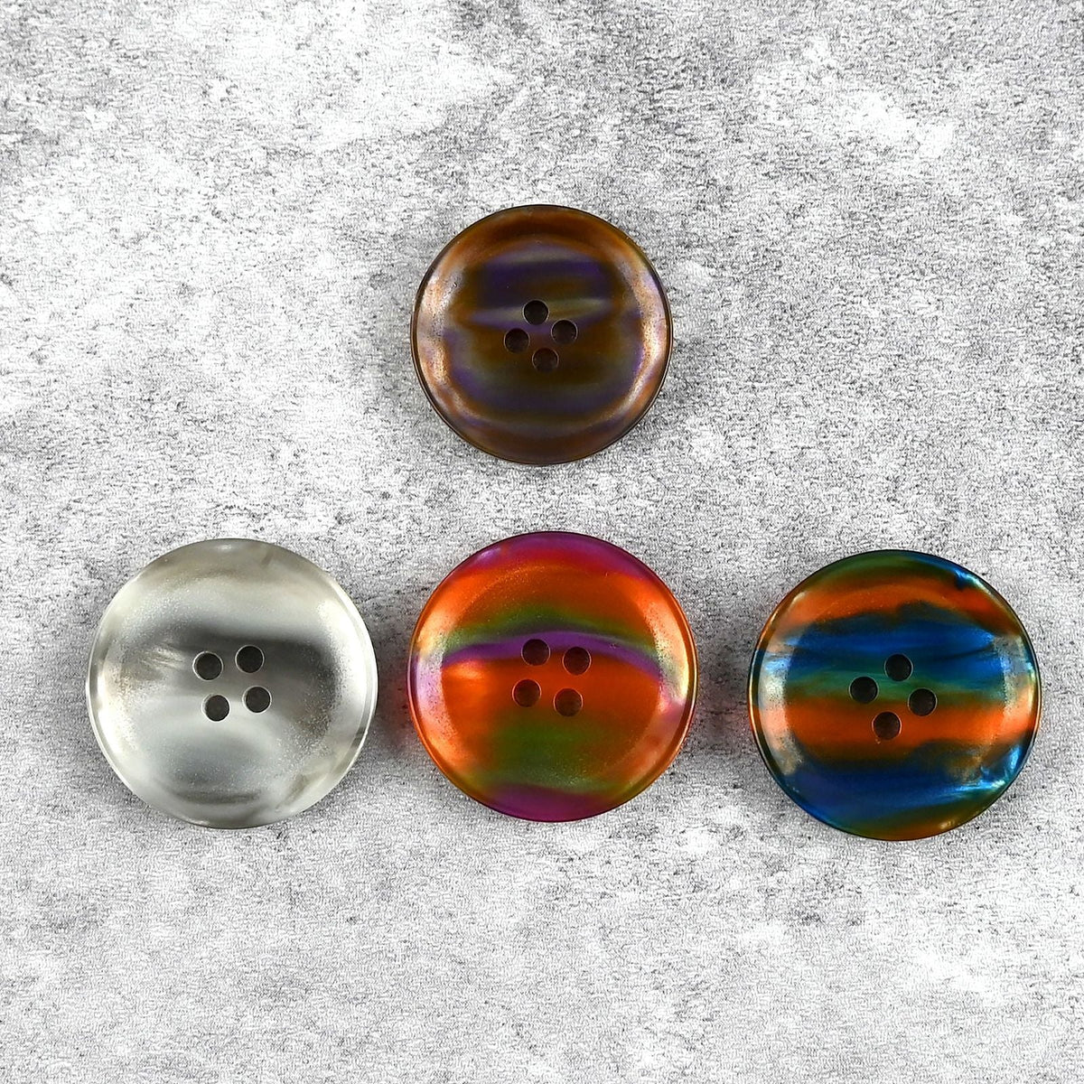 Four iridescent four-hole buttons in gray, orange-purple, and green-blue-orange tones