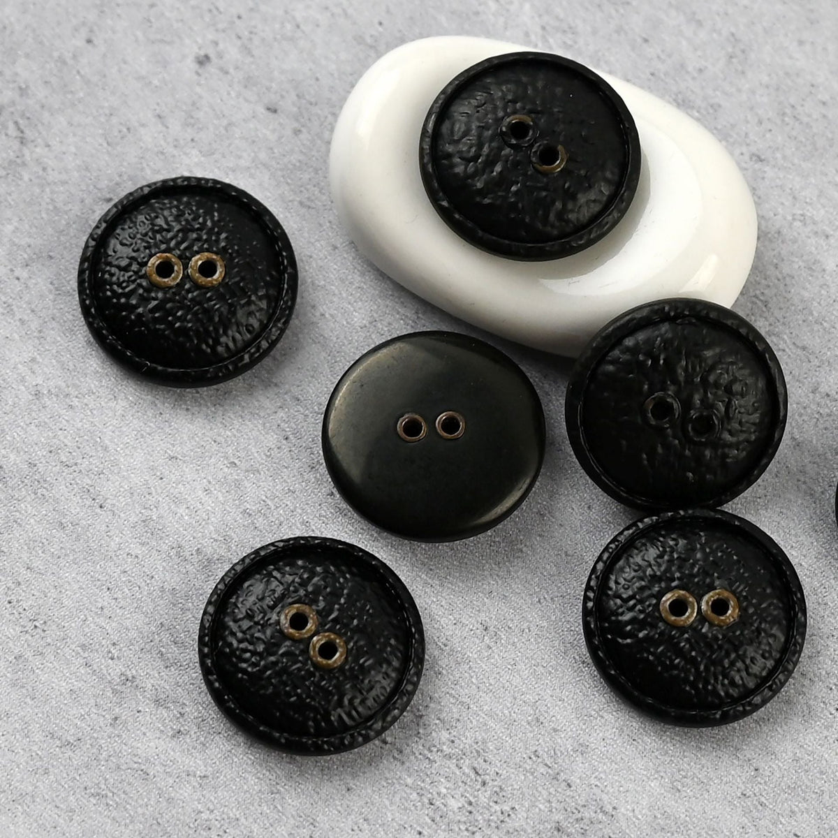 Black two-hole textured buttons with warm-toned eyelets