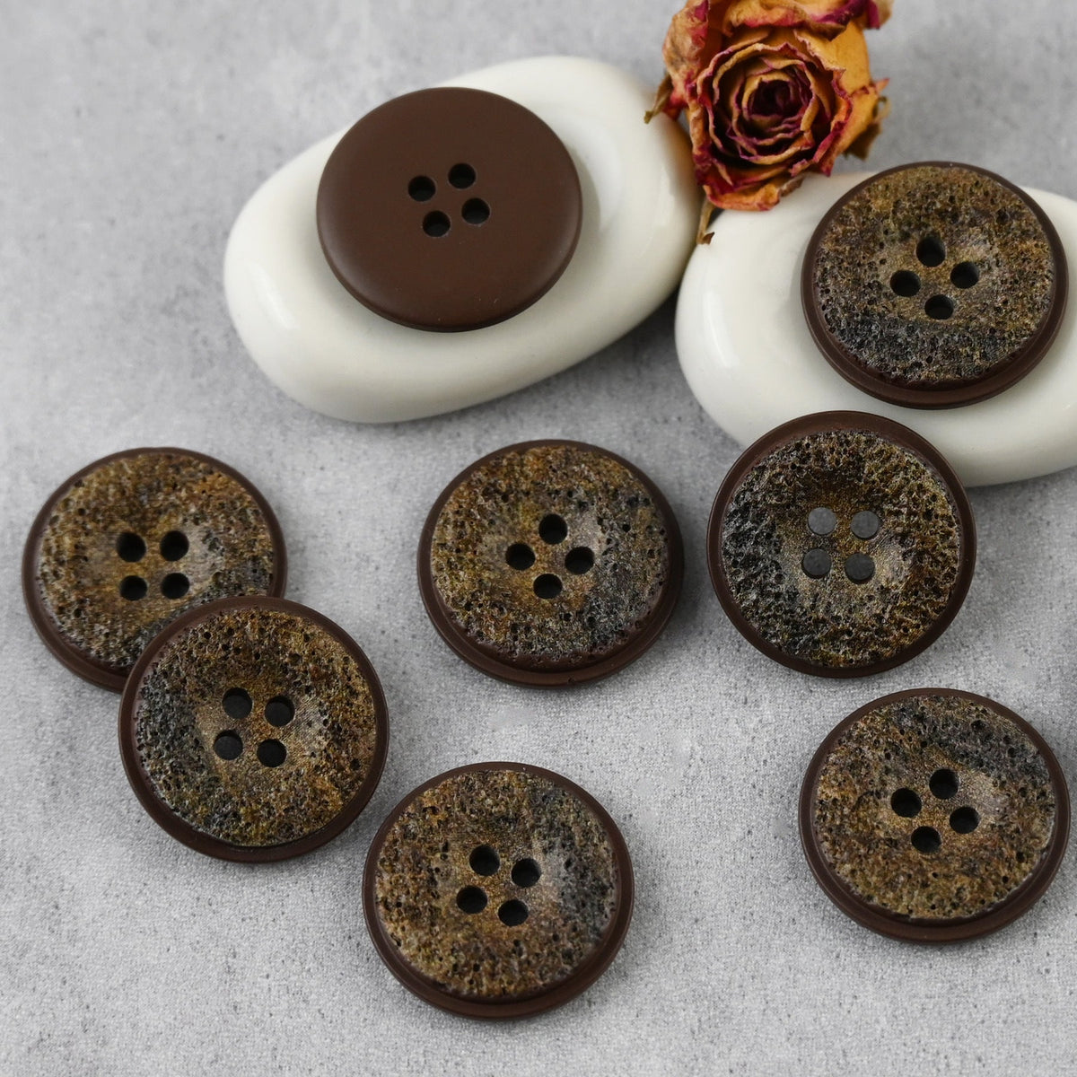 Brown pitted four-hole buttons with dark mottling