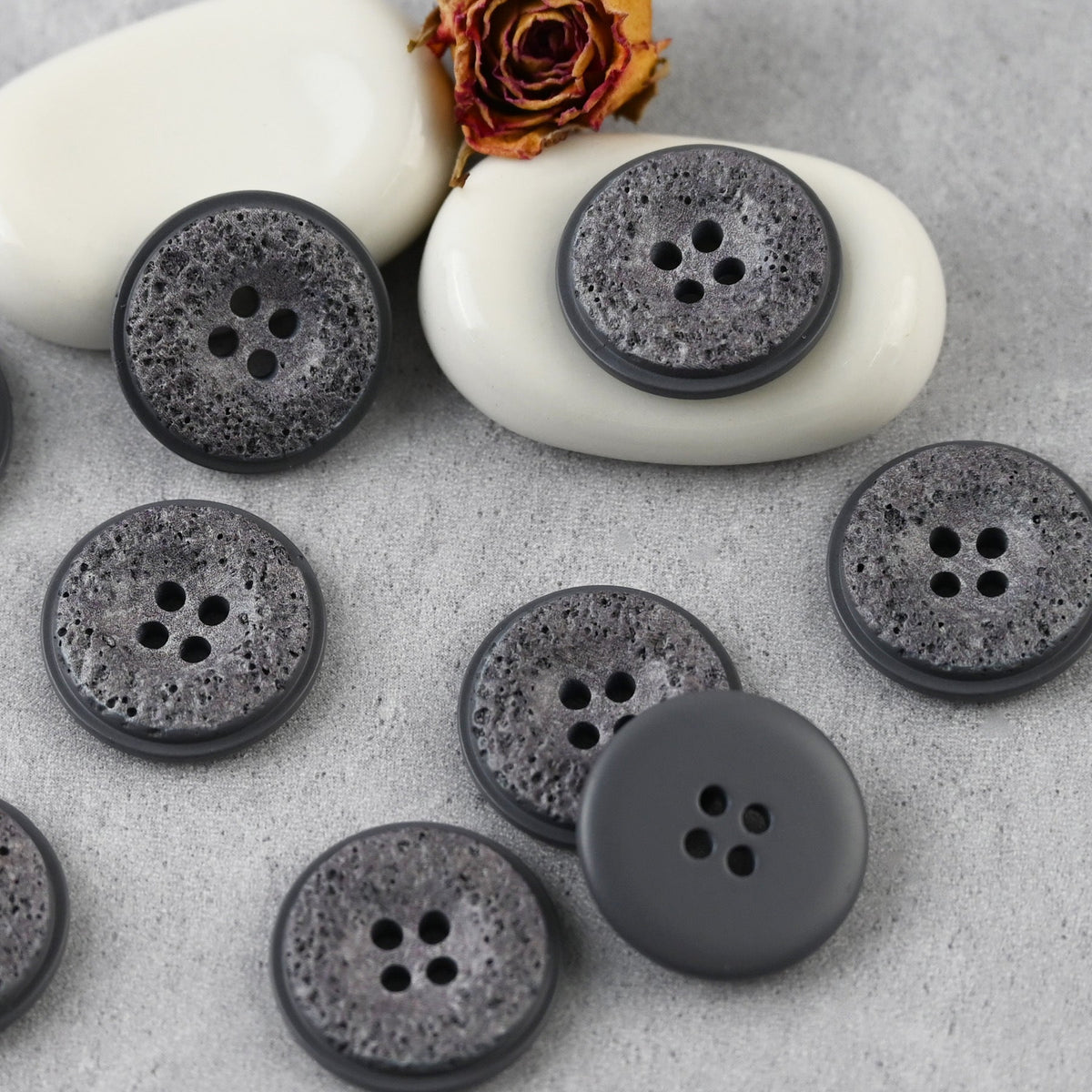Gray pitted four-hole buttons in a close arrangement