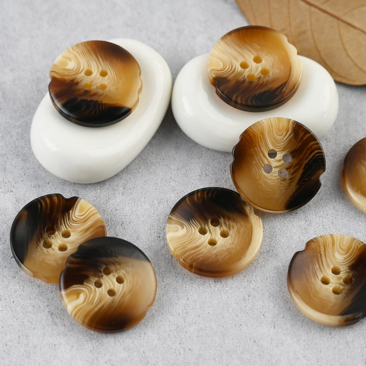 Brown four-hole buttons with notched edges and layered swirl patterns