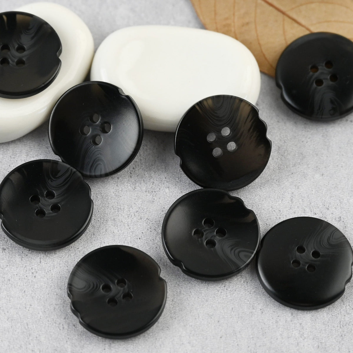 Black four-hole buttons with notched edges and subtle swirl patterns