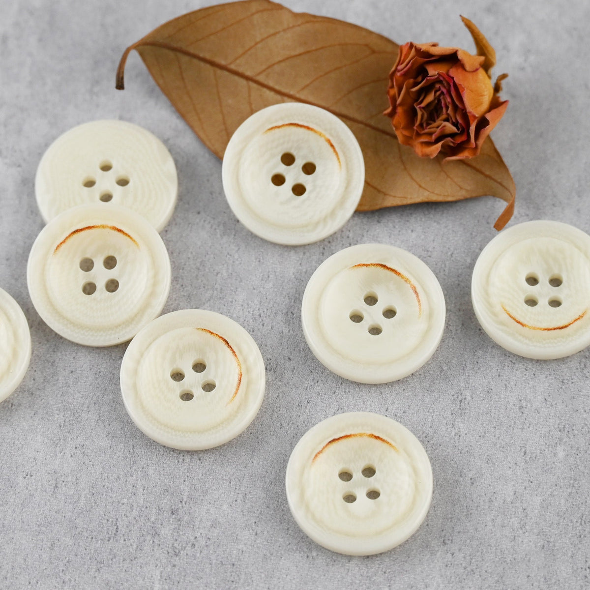 Cream four-hole buttons with raised rims and brown edge accents