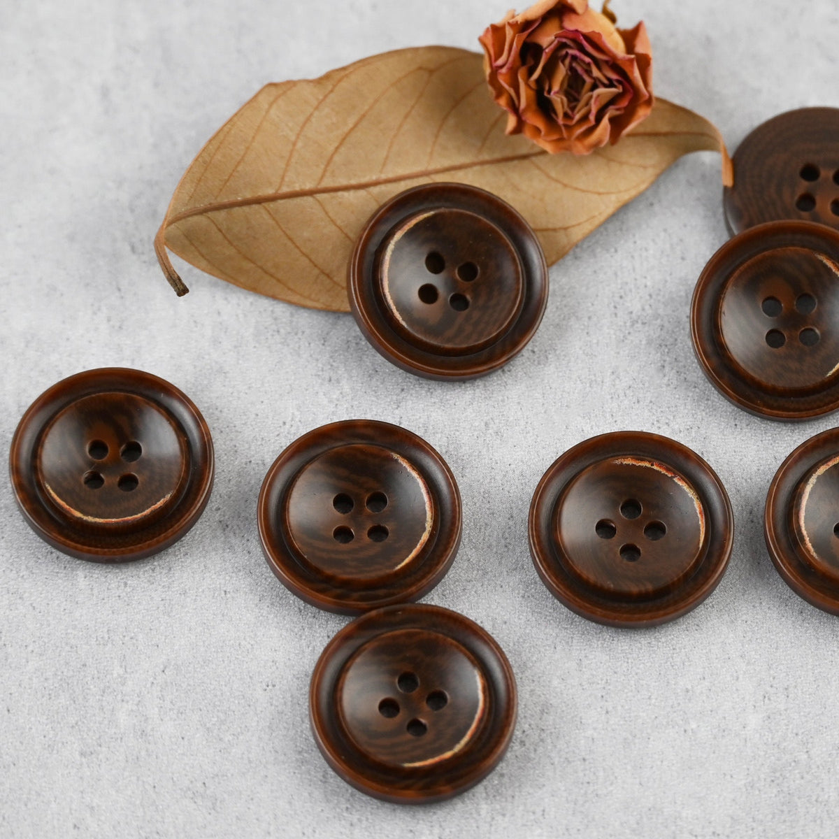 Brown four-hole buttons with stepped rims and warm edge accents