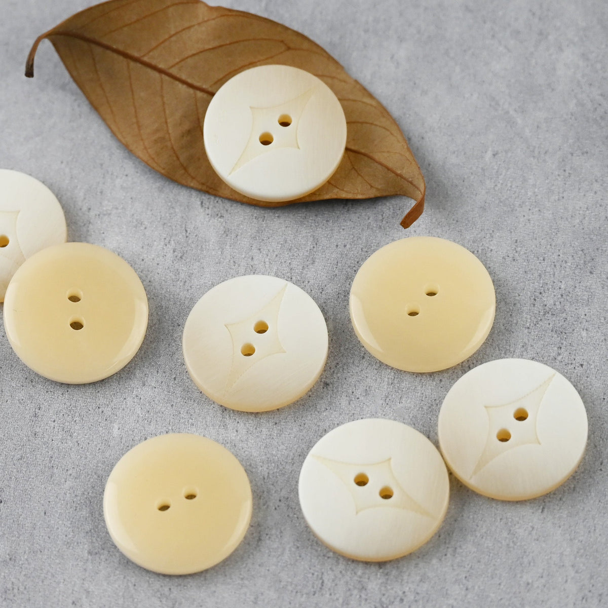 Cream two-hole buttons with curved center insets in varied sizes