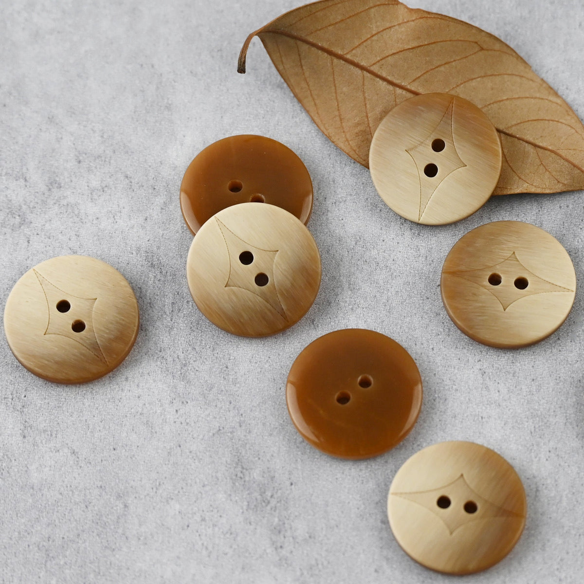 Light brown two-hole buttons with curved center insets in varied sizes