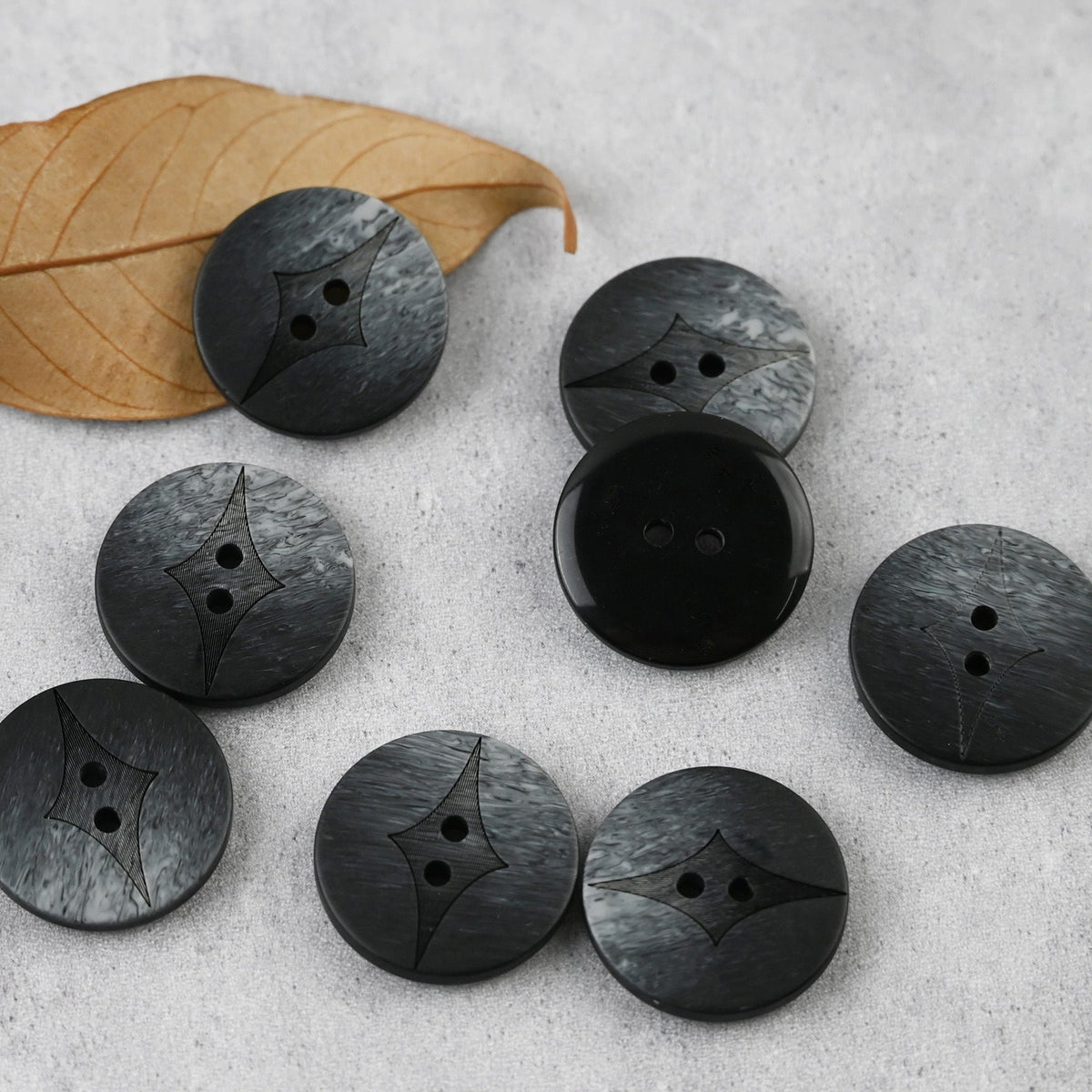 Black-gray two-hole buttons with curved center insets in varied sizes