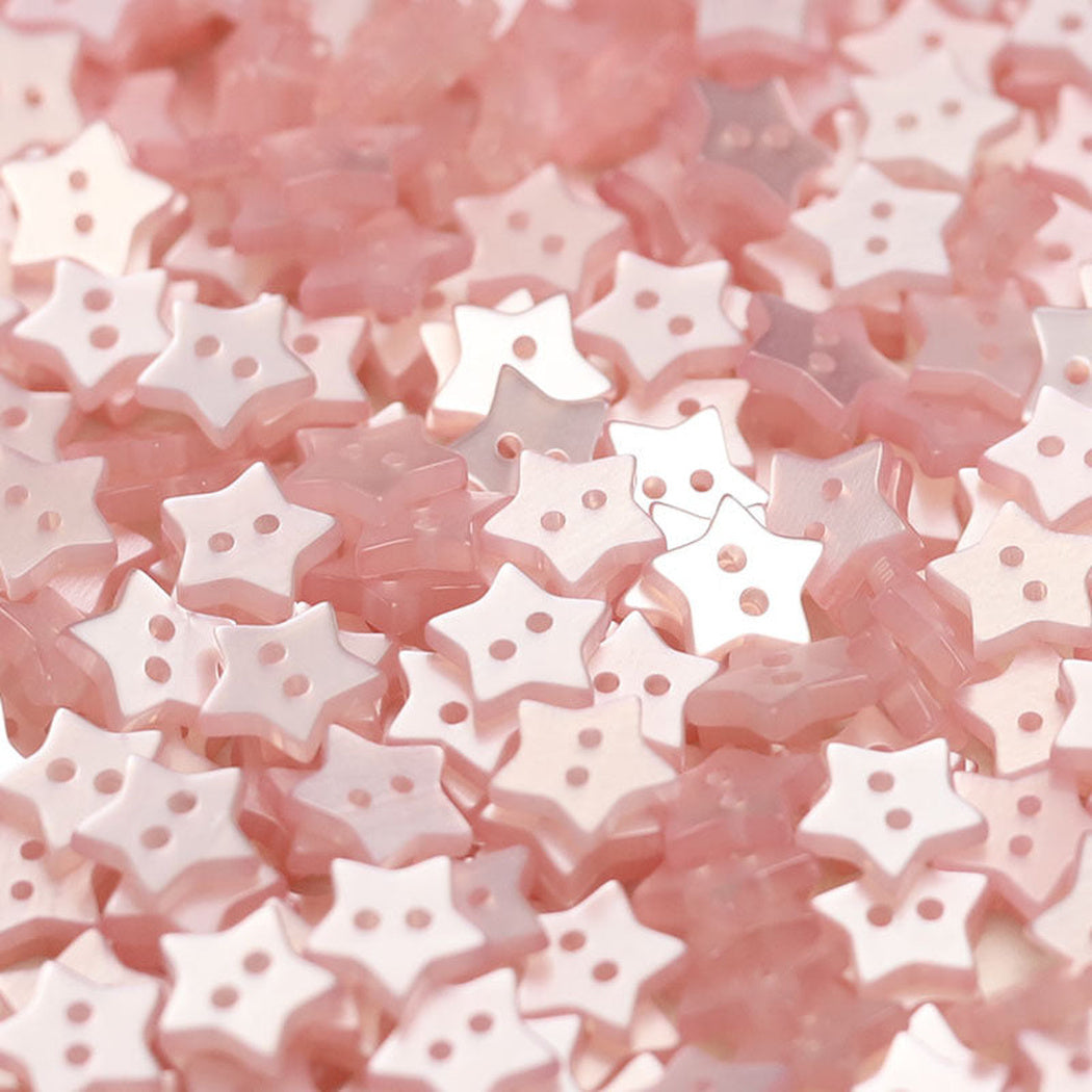 Close-up pile of light pink five-point star two-hole buttons