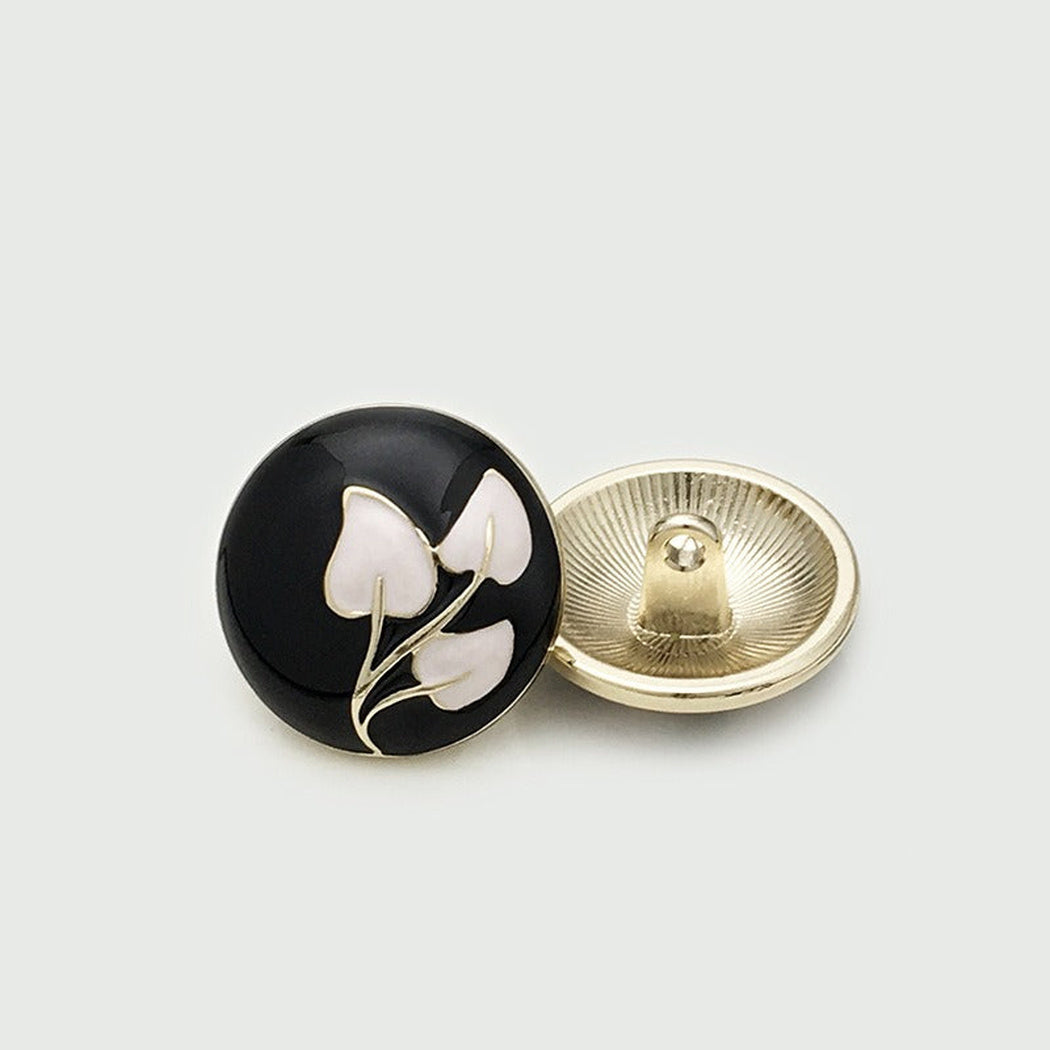 Black round shank button with white leaf motif, shown front and back