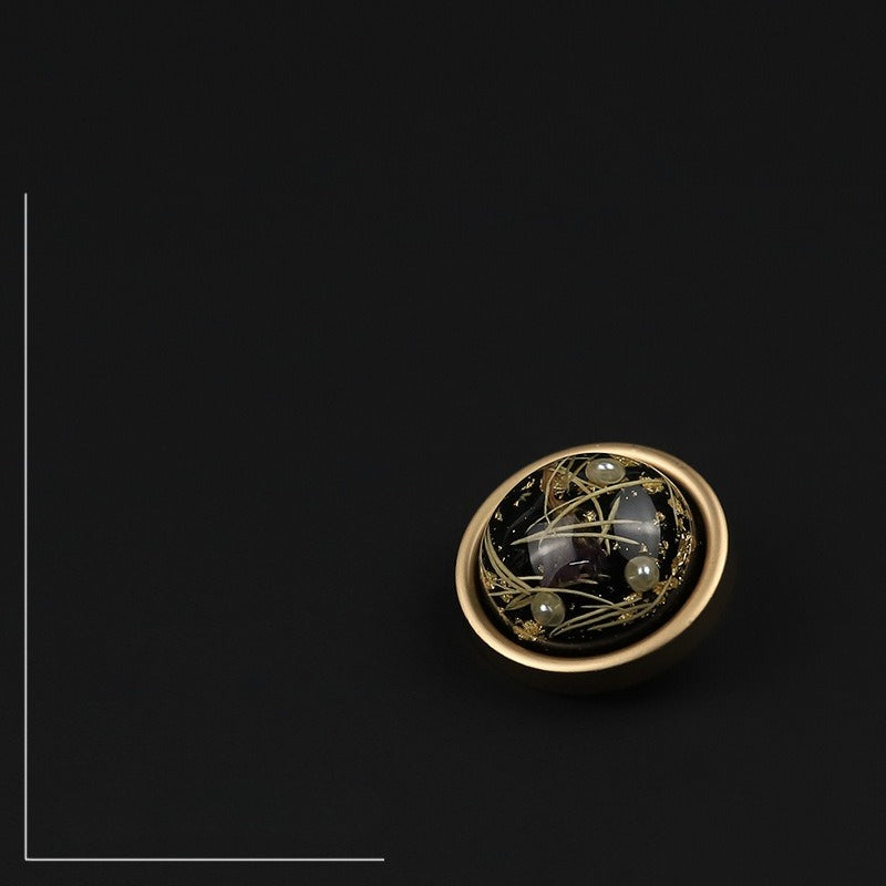 Black domed button with narrow rim viewed at an angle