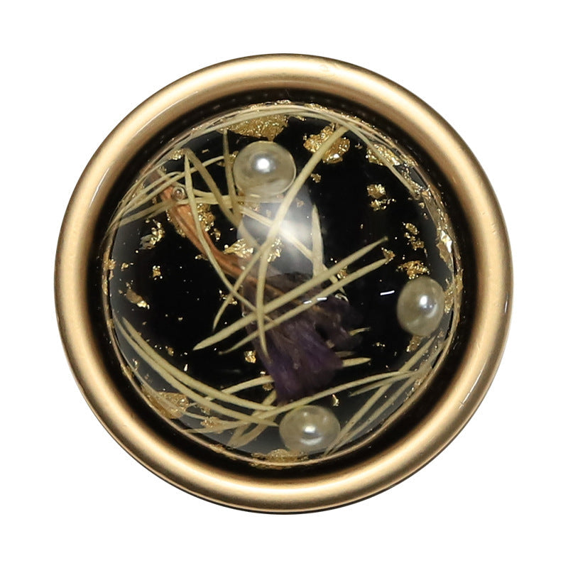 Black round button closeup showing crossing strands and round accents